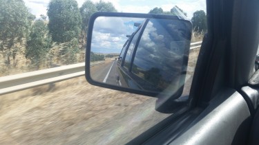 view of the road in the side mirror of the van