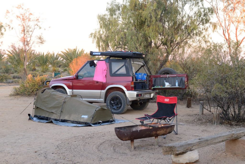 My campsite, Suzuki Vitara, swag and fire pit, surrounded by trees